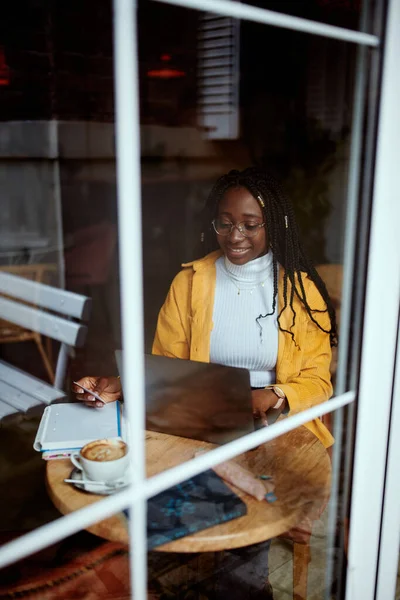 Çok kültürlü bir kız bir kafede oturuyor ve bilgisayarından internetten alışveriş yapıyor..