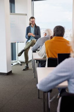 Genç bir eğitimci sınıftaki son sınıf öğrencilerinden oluşan çok kültürlü bir gruba ders veriyor..