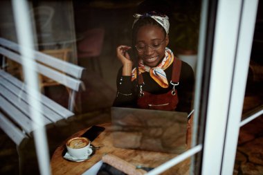 Çok kültürlü bir öğrenci bir kafede oturur ve dizüstü bilgisayardan konferans izler..