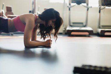Sporcu kadın spor salonunda dayanma tahtası yapıyor..