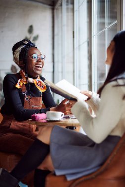 Kafeteryada oturan ve sınava çalışan iki çok kültürlü kız öğrenci..