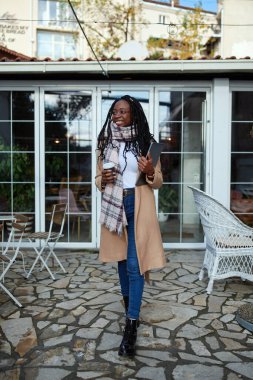 Kafenin önünde elinde bir bilgisayarla elinde kahveyle dolaşan bir serbest çalışan var..