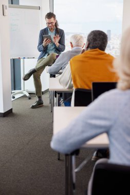 Genç bir eğitimci sınıftaki son sınıf öğrencilerinden oluşan çok kültürlü bir gruba ders veriyor..