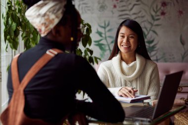 Kafeteryada oturan ve sınava çalışan iki çok kültürlü kız öğrenci..