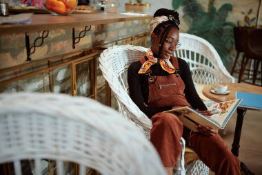 Çok kültürlü bir kız öğrenci kafeteryada öylesine oturur meyve suyu içer ve sınava çalışır..