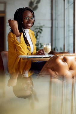 Zeki bir Afrikalı kız bir kafede oturur ve ders kitabına ödevlerini yazar..