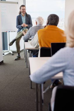 Genç hippi eğitimci, son sınıf öğrencilerinden oluşan çok kültürlü bir gruba sınıfta interneti nasıl kullanacaklarını öğretiyor..