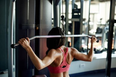 Kaslı bir sporcu spor salonundaki egzersiz makinesinde ağırlık kaldırıyor..