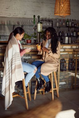 Çok kültürlü bir bayan arkadaş barda oturur, içki içer ve sohbet eder..