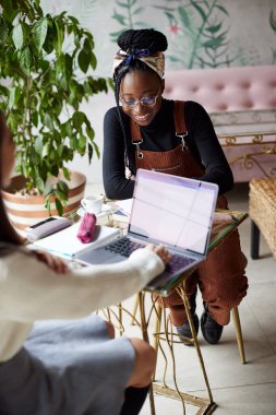 Kafeteryada oturan ve sınava çalışan iki çok kültürlü kız öğrenci..