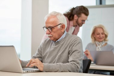 Son sınıf öğrencisi sınıfta oturuyor ve dizüstü bilgisayarında okul ödevini daktilo ediyor..