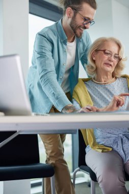 Dost canlısı genç bir öğretmen, son sınıf öğrencisi bir kız öğrencinin sınıfta dikilirken grafik tasarımı hakkındaki fikirlerini destekliyor..