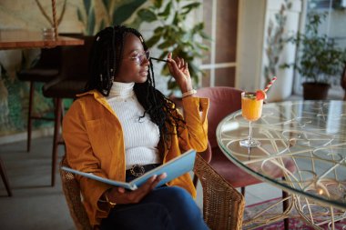 Rahat bir üniversiteli kız bir kafede oturup ders çalışıyor..