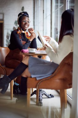 İki çok kültürlü öğrenci okul projesi için kafeteryada beyin fırtınası yapıyor..