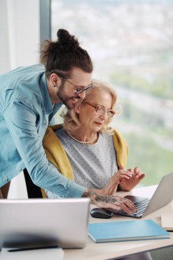 Dost canlısı genç bir öğretmen, son sınıf öğrencisi bir kız öğrencinin sınıfta dikilirken grafik tasarımı hakkındaki fikirlerini destekliyor..