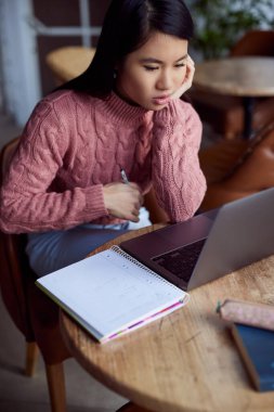 Kendini adamış çok kültürlü bir üniversiteli kız, kafede otururken dizüstü bilgisayardaki bir konferansı takip ediyor..