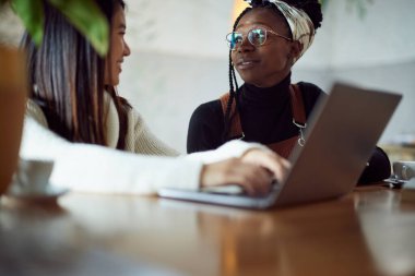 Kafeteryada oturan ve sınava çalışan iki çok kültürlü kız öğrenci..