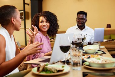 The businesspeople sit in a restaurant and have a business meeting during dinner.