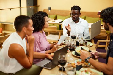 The colleagues at the dinner table in the restaurant sit and have a business meeting and brainstorm.