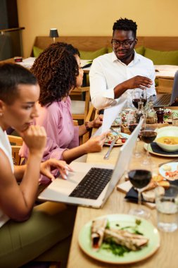 İş adamları bir restoranda oturur ve yemek boyunca iş toplantısı yaparlar..