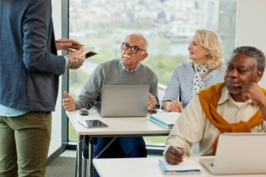 Bir grup son sınıf öğrencisi öğretmenleriyle aynı sınıfta oturuyor ve bir okul projesi üzerinde çalışıyorlar..