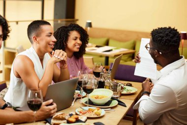 Multiracial businesspeople are having business dinner in a restaurant while having a presentation.