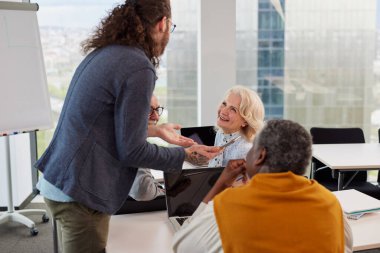 Genç bir öğretmen, çok kültürlü son sınıf öğrencilerine teknolojinin nasıl kullanılacağını öğretiyor..