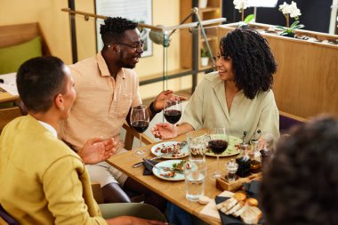 Küçük bir grup ırklar arası arkadaş bir restoranda yemek yiyor, konuşuyor, gülüyor ve eğleniyorlar..