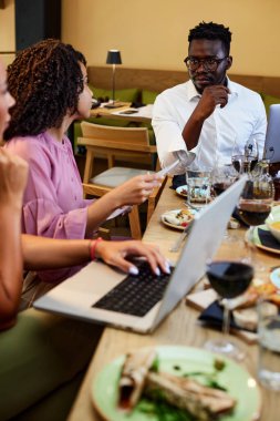 Bir grup ırklar arası iş adamı takım oluşturan bir restoranda oturmuş projeyi tartışıyorlar..