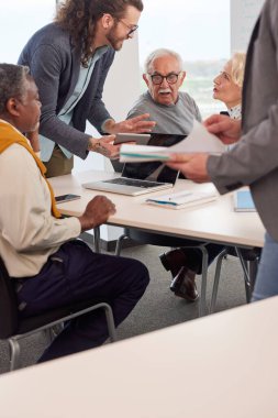Bir grup son sınıf öğrencisi öğretmenleriyle aynı sınıfta oturuyor ve bir okul projesi üzerinde çalışıyorlar..