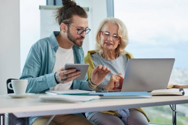 Genç bir profesör, son sınıf öğrencisinin yanına oturur ve web tasarımında ustalaşmasına yardım eder..