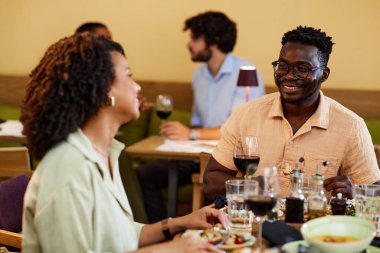 Restoranda yemek masasında eğlenen çok kültürlü bir çift..