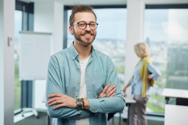 Portrait of a cheerful professor standing in a classroom with senior students.