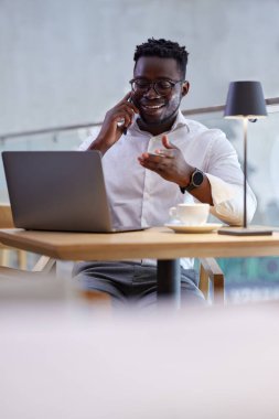 Odaklanmış bir Afrikalı restoran müdürü masada oturuyor ve dizüstü bilgisayardaki rezervasyonları kontrol ediyor..