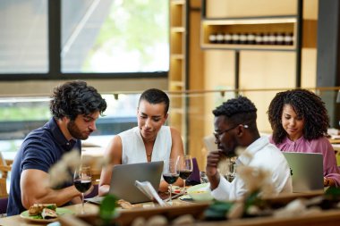 Meşgul iş adamları bir restoranda yemek masasında oturup dizüstü bilgisayarlar üzerinde çalışıyor ve önemli bir toplantı yapıyorlar..