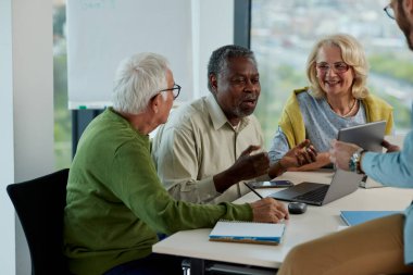 Bir grup son sınıf öğrencisi öğretmenleriyle aynı sınıfta oturuyor ve bir okul projesi üzerinde çalışıyorlar..