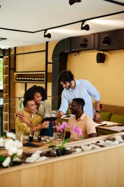 Irklar arası arkadaşlar kırmızı şaraplı bir restoranda başarı için kadeh kaldırıyorlar..