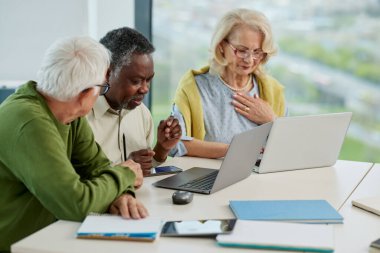 A multicultural group of senior students is doing an assignment on laptops in the classroom.
