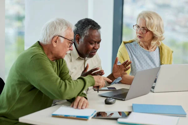 A multicultural group of senior students is doing an assignment on laptops in the classroom.