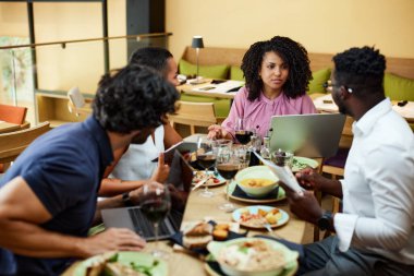 A female entrepreneur talks to the employees in a restaurant at the dinner table.