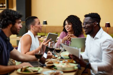 The coworkers sit together at the business meeting in a restaurant and talk about the project.