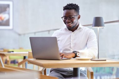 Bir kafede oturup dizüstü bilgisayarda yazan mutlu bir serbest yazar..