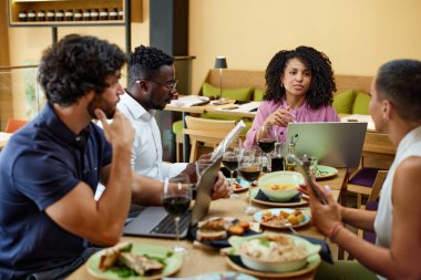 A female manager has a briefing with employees in a restaurant.