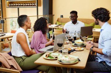 The businesspeople sit in a restaurant and have a business meeting during dinner.