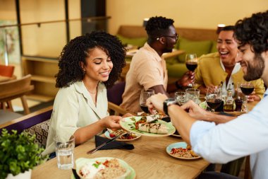 A group of cheerful friends are eating dinner in a restaurant.