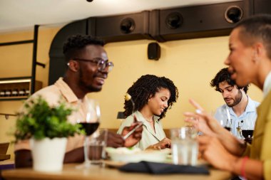 A group of cheerful friends are eating dinner in a restaurant.