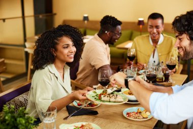 A group of cheerful friends are eating dinner in a restaurant.