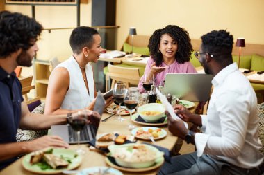The businesspeople sit in a restaurant and have a business meeting during dinner.