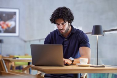 Freelancer sits in a coffee shop and finishes paperwork on the laptop. Hands are on the keyboard.