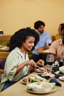 A Hispanic girl eats dinner in a restaurant.